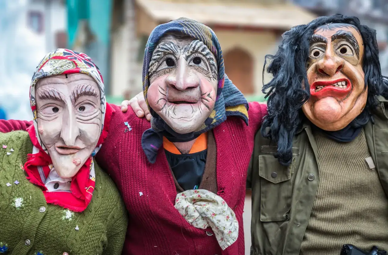 Tre maschere spaventose e colorate, con abiti tradizionali, celebrano il carnevale trentino.