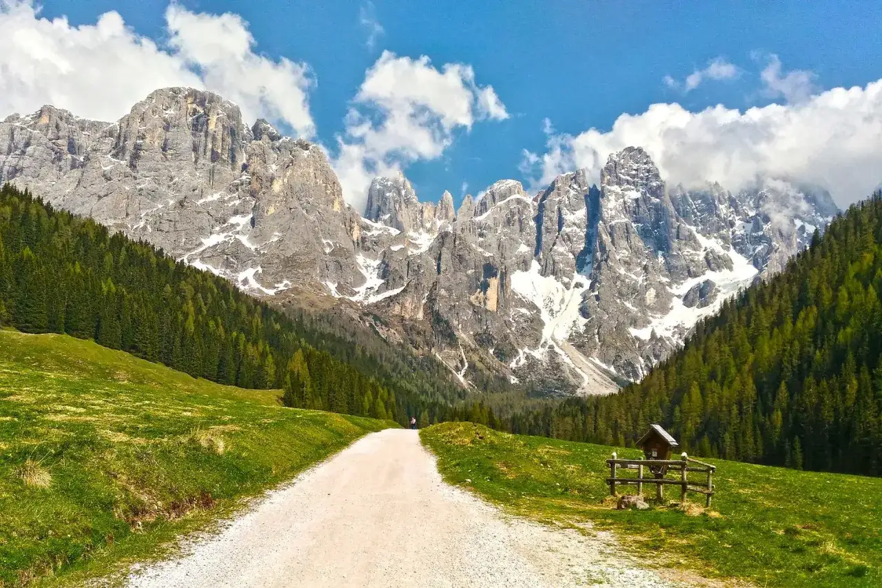 Sentiero in Trentino Dolomiti dove andare, tra prati verdi e imponenti vette innevate.