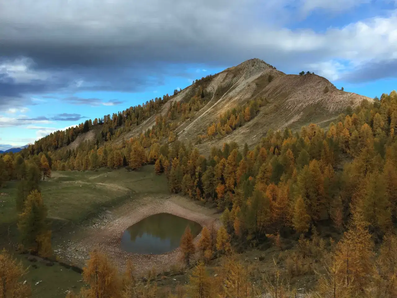 Autunno dorato sulle pendici montuose che circondano il lago delle salare, con un cielo nuvoloso che promette pioggia.