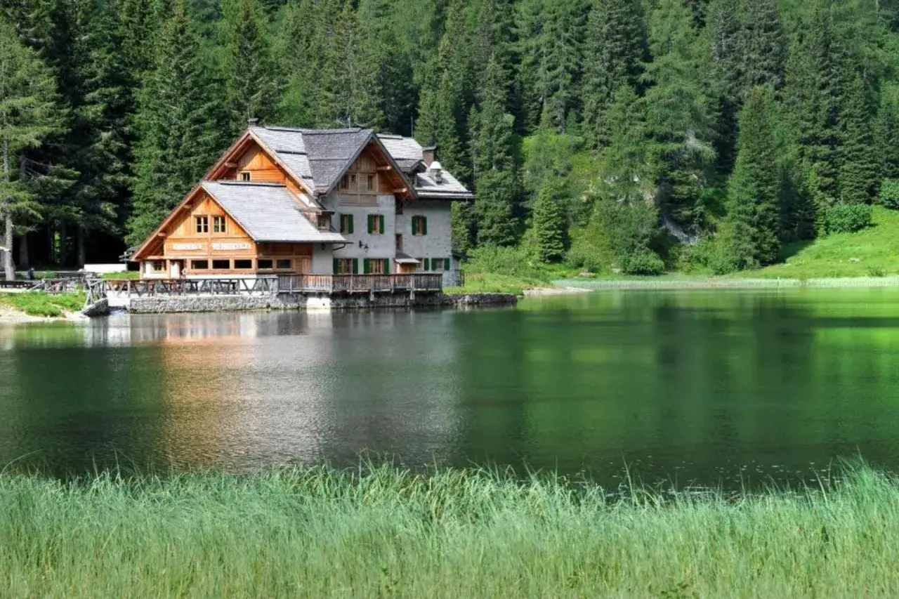 Rifugio sul lago Nambino, circondato da fitti boschi di conifere e verdi pascoli.