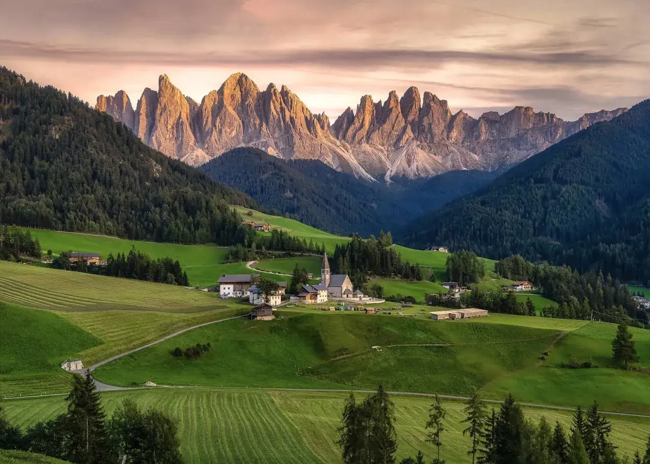 Villaggio alpino con chiesa e montagne imponenti. Un luogo incantevole per scoprire cosa vedere in Trentino Alto Adige.