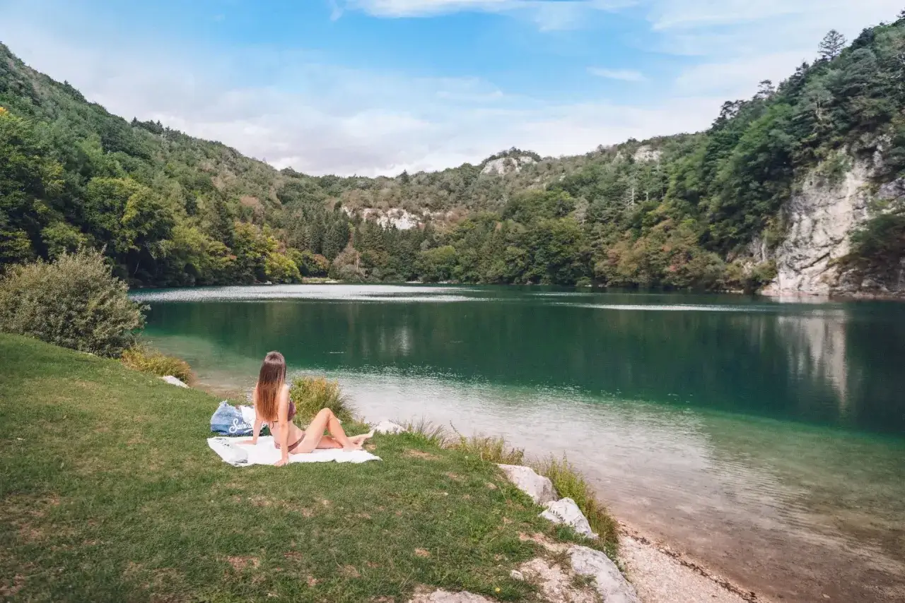 Donna rilassata sull'erba, con vista sul lago Lamar e le montagne verdi.