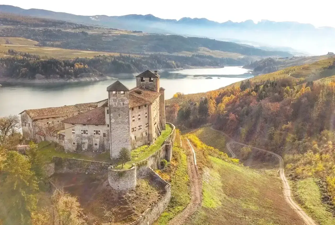 Antico castello domina il lago, circondato dai colori autunnali della Val di Non. Un luogo magico tra i castelli del Trentino.