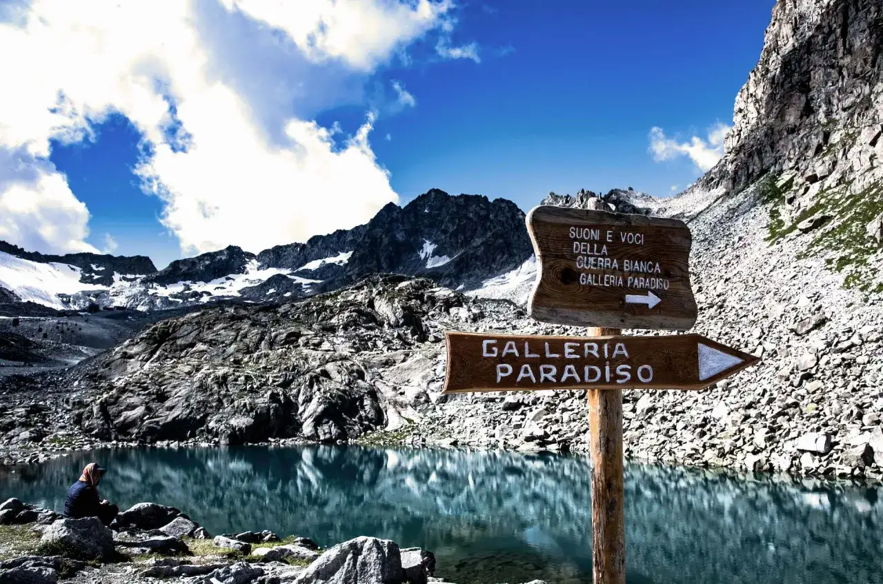 Lago alpino con cartelli che indicano la Galleria Paradiso, un luogo suggestivo al Passo del Tonale.