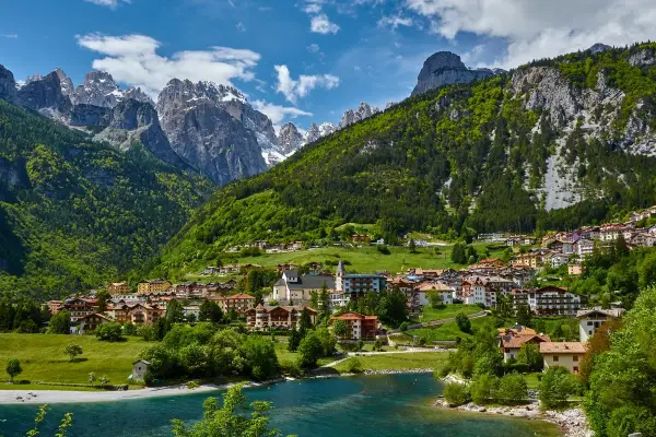 Villaggio alpino con case colorate e lago azzurro, incastonato tra montagne verdi e innevate. Ecco cosa vedere a Molveno per un panorama mozzafiato.