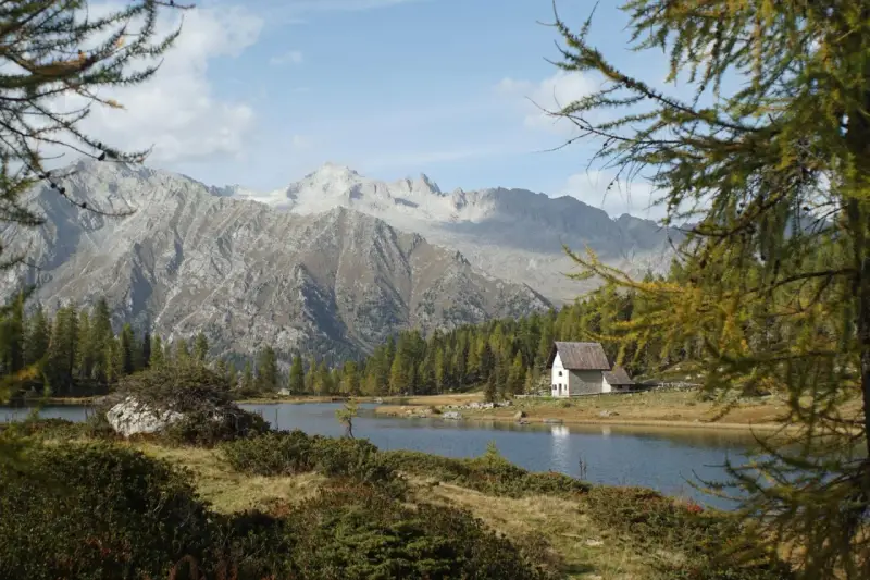 Un rifugio solitario si specchia nei laghi di San Giuliano, circondato da boschi e imponenti montagne.