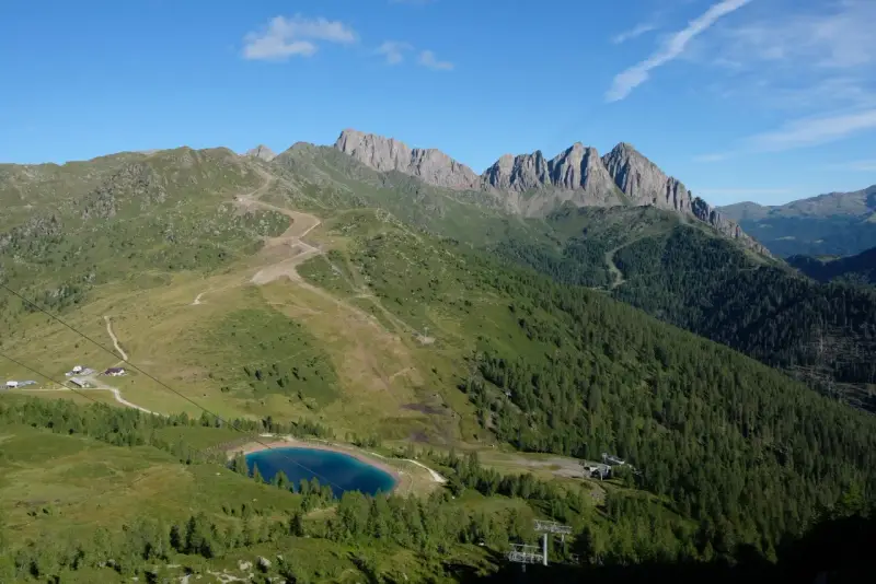 Panorami mozzafiato per passeggiate facili vicino a Trento. Un lago alpino azzurro e sentieri tra prati e boschi.