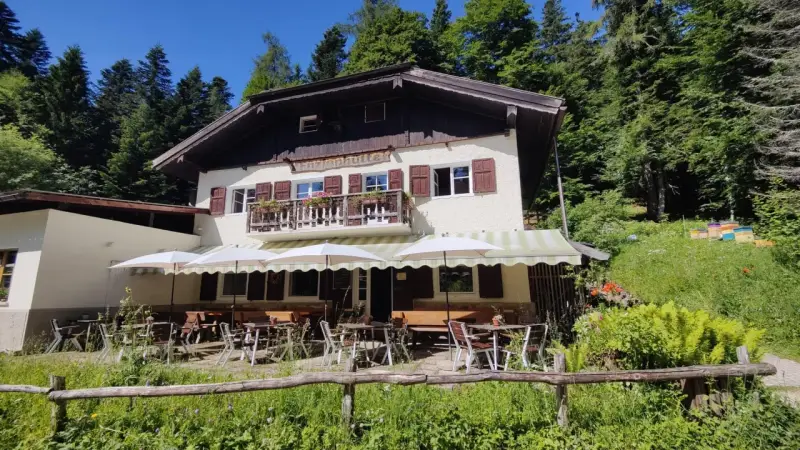 Rifugio alpino con tavoli all'aperto, ideale per rilassarsi dopo le ronzone passeggiate nel bosco.